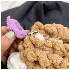 Close-up of brown and white crochet plush texture with silver metal lobster clasp detail