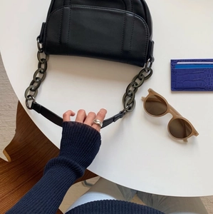 Detail of minimalist black leather shoulder bag with dark grey chunky chain decoration
