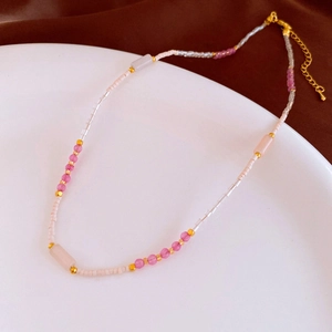 Close-up of handmade beaded necklace with pink stones and gold lobster clasp