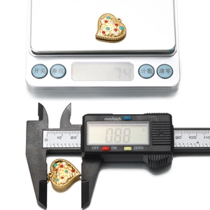 Detail showing weight and size measurement of checkered heart pendants on scale and caliper