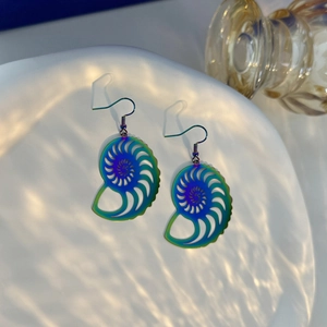 Macro detail of spiral seashell earrings with vibrant rainbow gradient metal finish