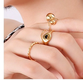 Detailed close-up of 18k gold plated titanium rings set with heart and bead designs on a hand