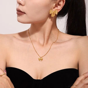 Golden brushed stainless steel bow stud earrings and necklace set on a model