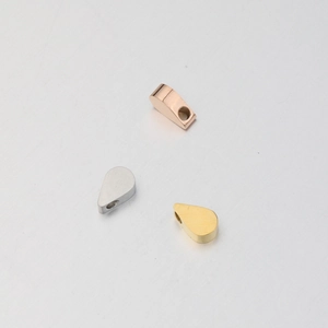 Macro detail of teardrop-shaped stainless steel charms in rose gold, silver, and gold finish