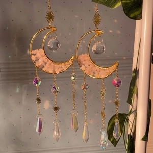 Detail of moon suncatcher featuring pink quartz chips and crystal prism hanging outdoors