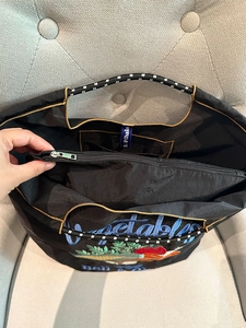 Close-up of lightweight nylon tote bag featuring inner zipper pocket and embroidery