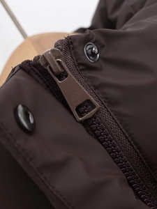 Macro view of the sleek zipper and metal snap button on the coffee brown padded vest