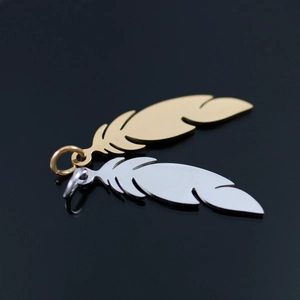 Macro shot of 18K gold and silver stainless steel feather pendants on black surface