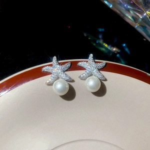 Gros plan détaillé des boucles d'oreilles perles étoile de mer avec strass scintillants