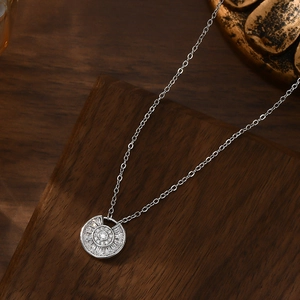 Detail of silver clover pendant necklace with micro-pave cubic zirconia on wood