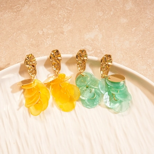Detail of gold geometric earrings with yellow and green shell-like tassel pendants
