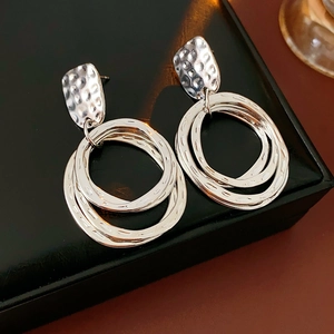 Detailed view of silver geometric layered drop earrings on a black leather jewelry box