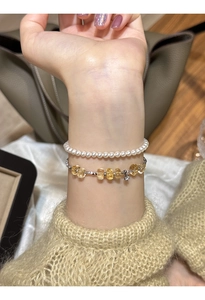 Close-up of layered bracelet with white pearls and yellow citrine stones on a wrist