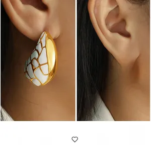 Détail macro de boucles d'oreilles vintage en forme de goutte avec émail et motifs dorés