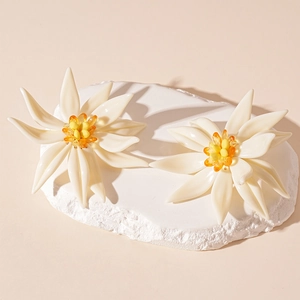 Macro shot of white resin flower earrings with yellow crystal beads on a stone base
