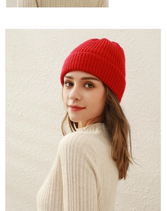 Close-up detail of a bright red ribbed knit beanie hat worn by a model in winter