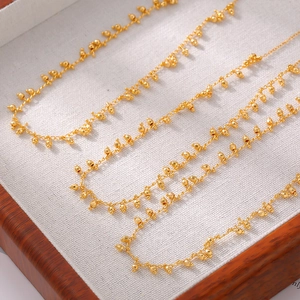 Elegant 18k gold plated copper necklace with ball tassels on a white velvet display