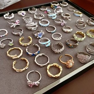Close-up of assorted heart and floral zircon rings organized in a grey jewelry display tray