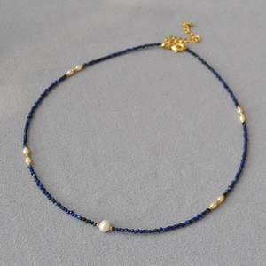 Detail shot of dainty lapis lazuli beads and freshwater rice pearls on golden necklace