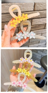 Detailansicht großer Haarklammern mit Kristallblumen und mattem Gelee-Finish in der Hand