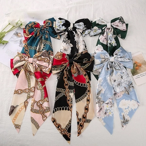 Detailed view of three vintage silk floral bow hair clips with long elegant streamers