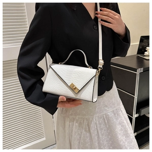 Detail of white crocodile pattern shoulder bag featuring a gold twist lock and chic texture