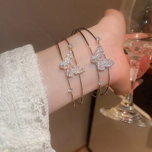 Detail of a butterfly cuff bracelet with pink zircons and gold finish on a model