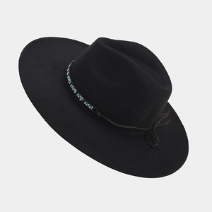 Detailed shot of ethnic turquoise beads and brown tassel trim on black felt fedora hat