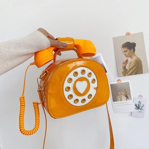 Detail of vintage creative telephone-shaped shoulder bag in glossy orange patent leather