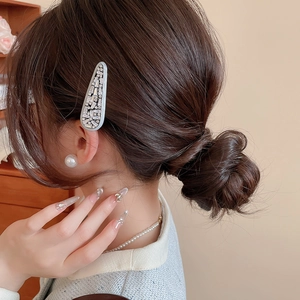 Detail of a grey-blue teardrop hair clip with sparkling rhinestones on model's hair
