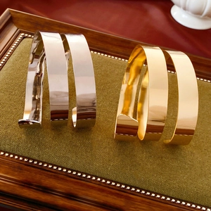 Detail view of spiral layered metal bangles in gold and silver on a green velvet tray