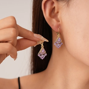 Vintage luxury gold geometric rhombus drop earrings with purple crystals on a model