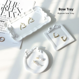 Detailed view of three white gypsum bow trays in round, square and rectangular shapes