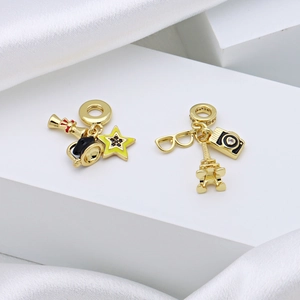 Gold plated Eiffel Tower and camera charms for bracelets on a white silk background