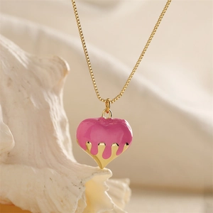 Dettaglio del ciondolo a cuore rosa con effetto oro colato su una collana a catena