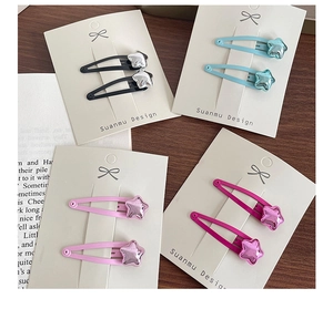 Close-up of colorful star-shaped metallic hair clips on display cards on wooden background