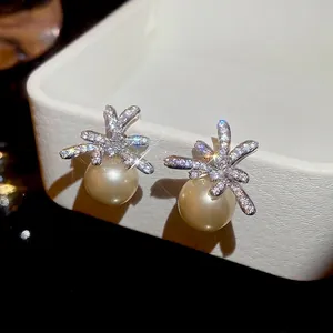 Elegant silver starburst stud earrings with micro-pave zircons and round gold pearls