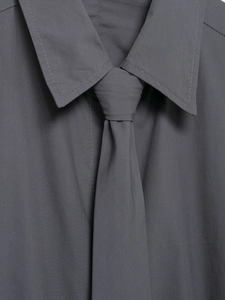 Detail of dark gray poplin shirt collar with matching narrow tie in macro view