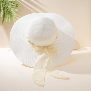 Detailed texture of white wide-brim straw hat with yellow ribbon bow and pearl accents