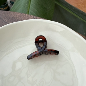 Close-up of tortoise shell pattern hair clip on a ceramic tray with natural lighting