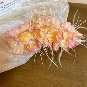 Détail de la pince à cheveux fleurie avec papillon en cristal et plumes blanches