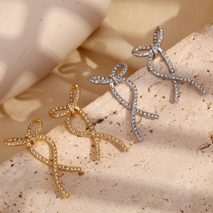 Close-up of gold and silver twisted ribbon stud earrings with shimmering rhinestones