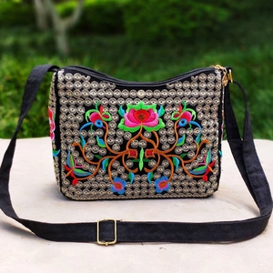 Detailed close-up of ethnic floral embroidery on a black canvas crossbody bag