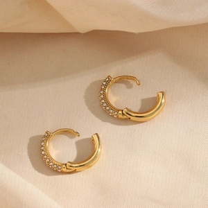 Dettaglio di orecchini a cerchio placcati oro 18K con pavé di zirconi su tessuto di seta