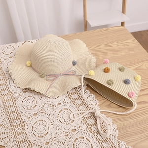 Close-up of children straw hat and matching bag set with colorful plush rainbow balls