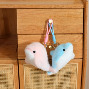 Detail of cute plush dolphin keychains in pink and blue with braided ropes and metal rings