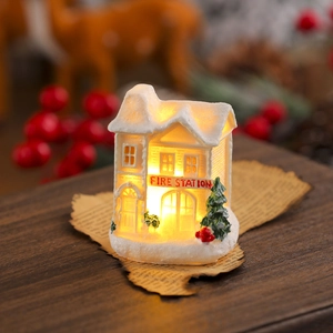 Macro detail of snow-covered white resin Christmas fire station with warm LED lights