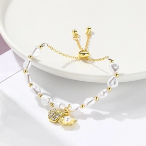 Detail of baroque pearl bracelet with gold seashell charms and adjustable slider clasp