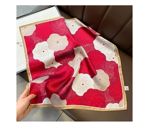 Close-up of silk square scarf featuring elegant red floral patterns and gold-edged borders