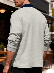 Detail of light gray long sleeve polo shirt with navy collar and fine knit texture